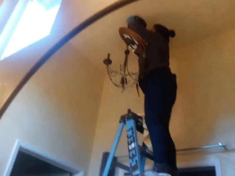 Electrician installing a chandelier in a Howards Grove residence